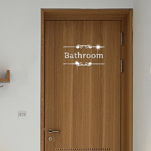 Close-up of silver acrylic mirror Bathroom sign with elegant streamline decor on a wooden door