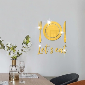 Detailed view of gold mirror acrylic 'Let's eat' wall art stickers in a modern dining room