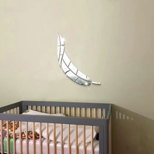 Modern acrylic feather mirror wall sticker shown above a wooden crib in a nursery
