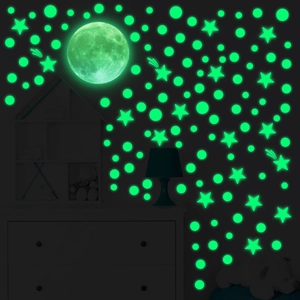 Luminous wall stickers set with moon stars and dots glowing bright green in the dark bedroom