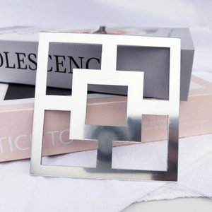 Macro shot of a modern silver mirror acrylic square hollow wall sticker on books