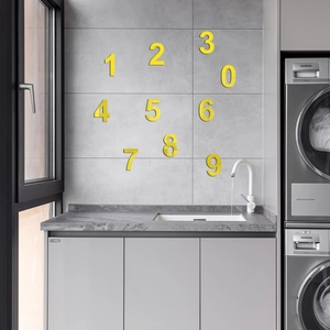 Detail view of 3D yellow acrylic mirror number wall stickers on a grey tiled bathroom wall