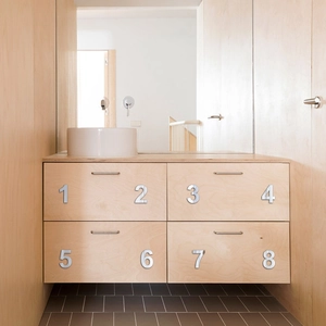 Close-up of modern mirrored acrylic numbers 1 to 8 on minimalist wooden drawer panels