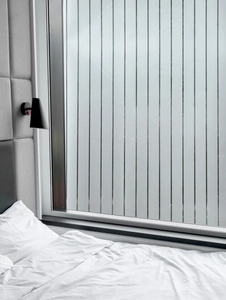 Close-up of frosted privacy film with vertical stripes on bedroom window glass