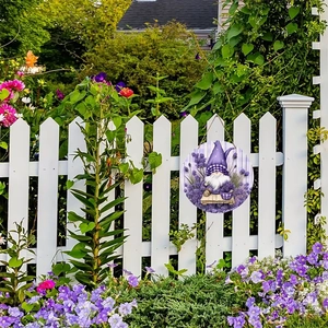 Lavender gnome garden welcome sign hanging on a white fence with purple flowers