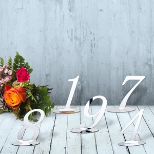 Silver mirror acrylic table numbers with round bases displayed on a vintage wood background