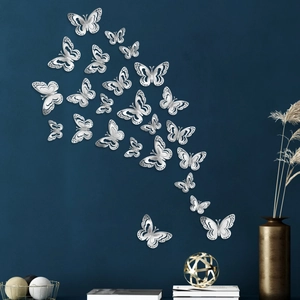 3D metallic silver hollow butterfly wall stickers displayed on a dark blue interior wall