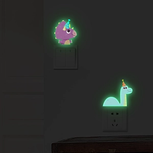 Glow-in-the-dark dinosaur wall stickers showing green luminous effect on light switch