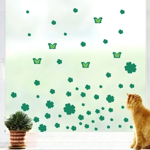 Window glass decorated with green clover stickers, yellow butterflies and a cute ginger cat