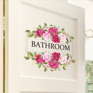 Close-up of pink and red rose floral wall sticker with Bathroom lettering on a white door