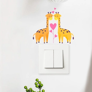 Detail of cartoon giraffe wall stickers with pink hearts above a white light switch