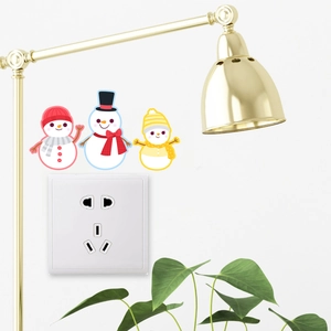 Three cute cartoon snowman stickers applied above a light switch on a white wall decor