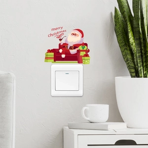 Detailed view of Santa Claus and gift box stickers on a white wall light switch cover