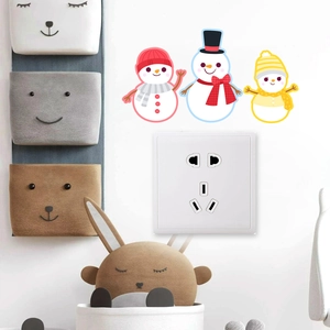 Detailed view of three cute cartoon snowman wall stickers placed above a power socket