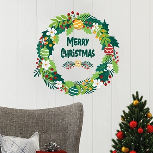 Macro shot of Merry Christmas wall sticker with green leaves and berries on wooden wall