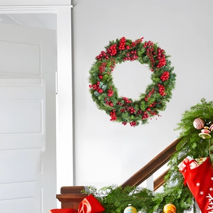 Couronne de Noël avec aiguilles de pin vertes et baies rouges sur un mur blanc décoré