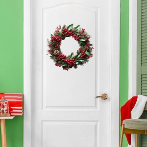 Detailed Christmas wreath featuring red berries, pine cones and holly leaves on a white door