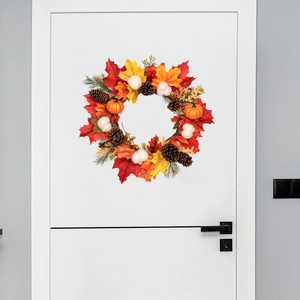Couronne d'automne aux feuilles d'érable rouges et mini citrouilles sur porte blanche