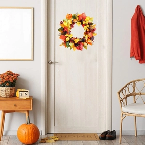 Detail of autumn wreath with maple leaves and berries hanging on a white wooden door