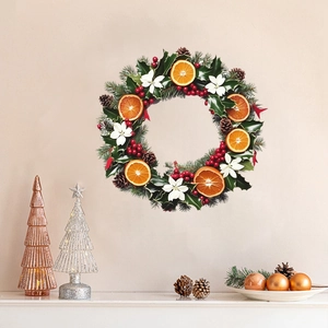 Detailed view of a Christmas wreath with pine cones, dried oranges, and red berries on a wall