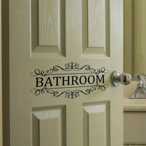 Elegant black Bathroom wall sticker with vintage scroll design on a beige wooden door