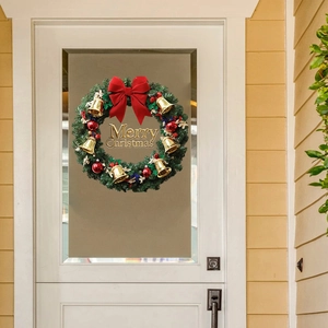 Christmas wreath with red bow, golden bells and Merry Christmas sign on white door