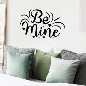 Detail of Be Mine wall sticker with heart and cross elements above bedroom pillows