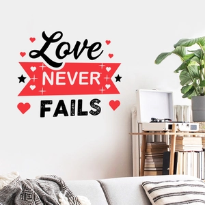 Détail du sticker mural Love NEVER FAILS avec cœurs rouges dans un salon cosy