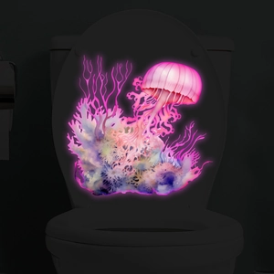 Adesivo murale luminoso con meduse rosa e coralli brillanti sul coperchio del water al buio