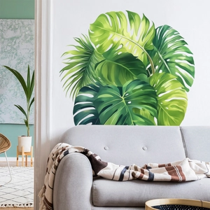 Tropical monstera and palm leaf wall stickers on white wall above a gray sofa