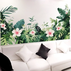 Tropical wall sticker with monstera leaves and hibiscus flowers over a white sofa