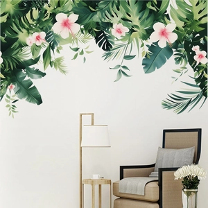 Tropical wall stickers with monstera and hibiscus flowers displayed above a beige sofa