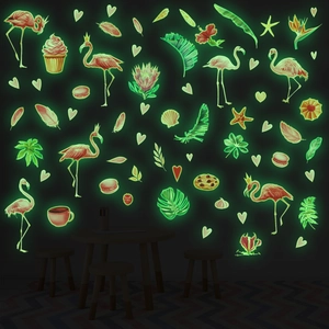 Luminous wall stickers featuring green glowing flamingo and tropical leaves in dark room