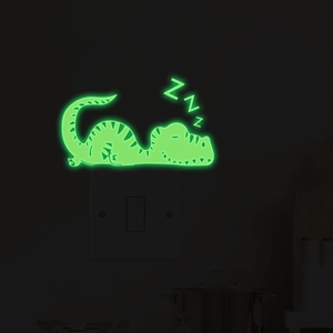 Glow-in-the-dark sleeping dinosaur wall sticker showing luminous green effect at night
