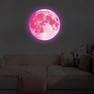 Detail of pink luminous moon wall sticker glowing in a dark children's bedroom setting