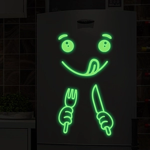Luminous green cartoon face stickers showing glow-in-the-dark effect in dark kitchen decor