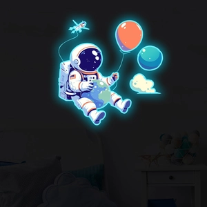 Glow-in-the-dark astronaut wall sticker with planet and balloon emitting cool blue neon light