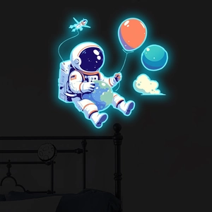 Close-up of luminous astronaut wall stickers glowing in a dark themed children bedroom