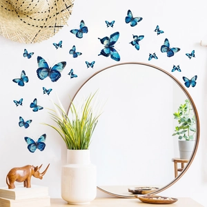 Stickers muraux papillons bleus lumineux sur mur blanc autour d'un miroir décoratif
