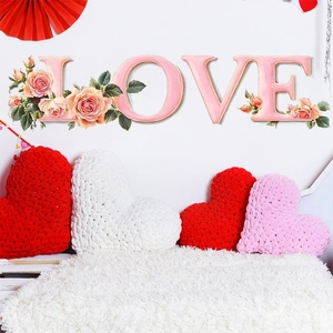 Detail of red and white heart-shaped crochet pillows with LOVE wall stickers for Valentine