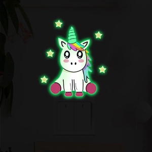 Glow-in-the-dark unicorn and star wall stickers showing green fluorescence at night
