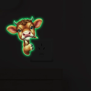 Luminous cartoon cow wall sticker showing green glow effect on a light switch in the dark