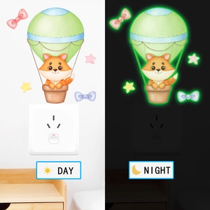 Sticker mural lumineux montrant un renard en montgolfière, vue jour et nuit