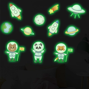 Luminous wall stickers featuring cartoon space animals and planets in a dark bedroom