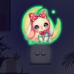 Close-up of a green glowing rabbit sticker on a crescent moon placed on a wall switch