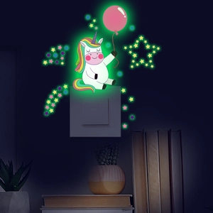 Luminous unicorn wall sticker with stars glowing green in dark bedroom setting