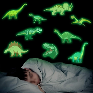 Stickers muraux dinosaures fluorescents montrant l'effet lumineux dans une chambre d'enfant