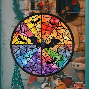 Detail of round Halloween window cling featuring bats and spider web on store glass