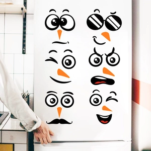 Close-up of cute cartoon snowman face stickers applied on a white refrigerator door