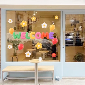 Detailed view of colorful 3D-style Welcome lettering and floral decals on shop glass